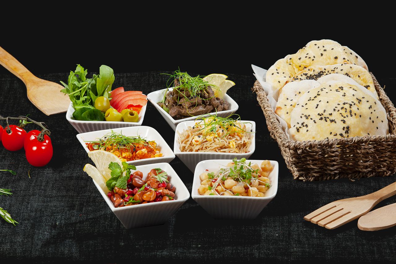 services-02 A vibrant mezze platter with Middle Eastern dishes and fresh bread, perfect for sharing.