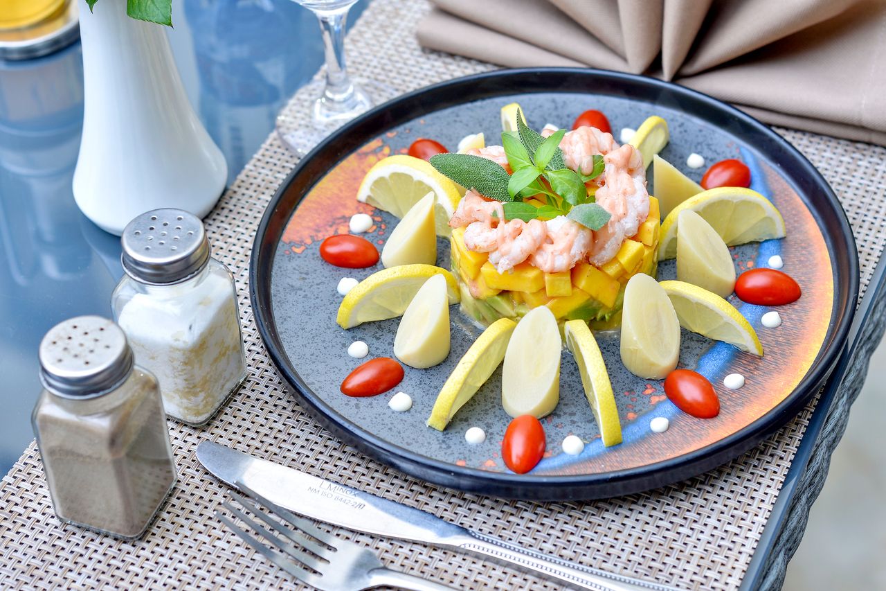 who-we-are A stylish seafood dish garnished with lemon, cherry tomatoes, and mint, perfect for a gourmet starter.