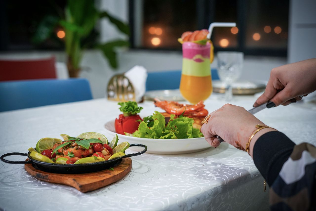 our-story An elegant dining table setup with a colorful cocktail, fresh salad, and plated dish ready to serve.